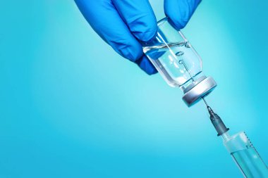 Vaccine in a vial with a syringe on a blue background.The concept of medicine, healthcare and science clipart