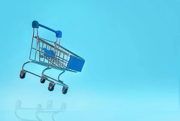ショッピングカートは青い背景に飛んでいます オンラインショッピングの薬の概念 テキストのコピースペース — ストック写真
