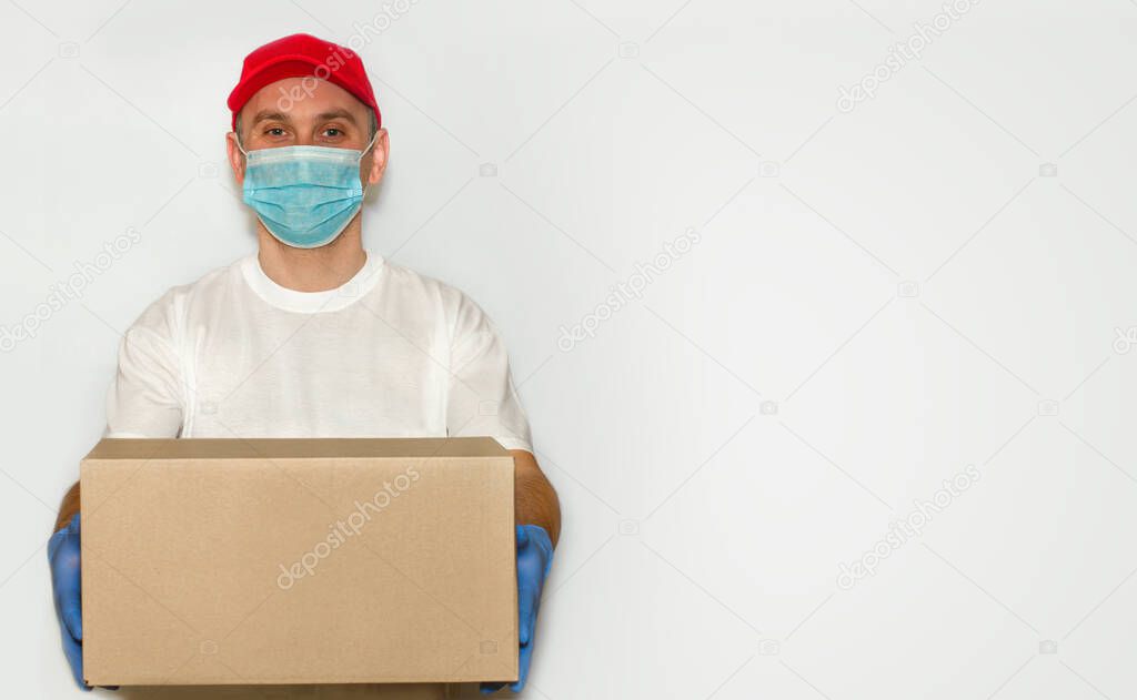 Delivery employee delivering cardboard box in medical gloves and mask.?oncept of safety mail goods courier delivery in virus or coronavirus quarantine. ?opy space on white background