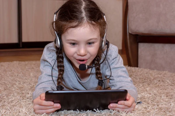 Distance home education online. We are sitting at home. Schoolgirl with a tablet and headphones with a microphone. Quarantine