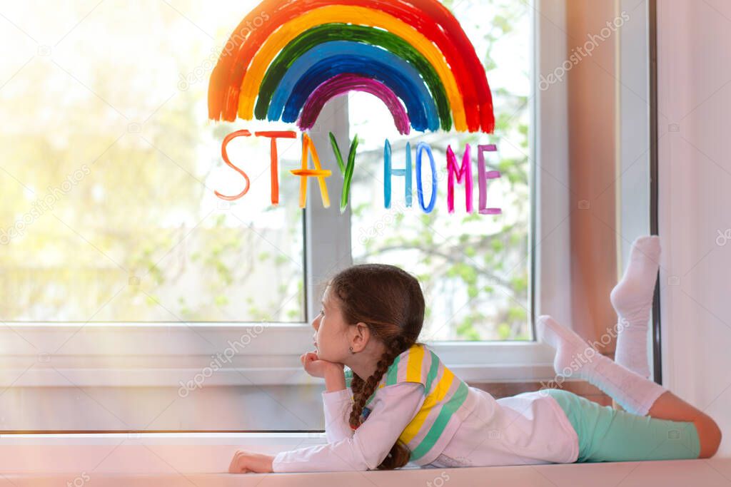 A beautiful girl lies on a window sill and looks out the window with a painted rainbow and the test 