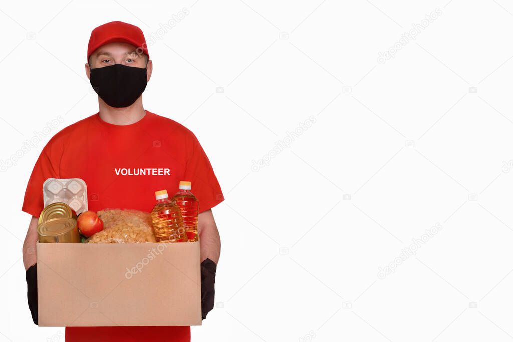 Valunteer in protective gloves and a mask holds a box on a light background. Donation concept. Voluntary assistance to those in need.?oncept goods in virus or coronavirus quarantine. ?opy space on white background
