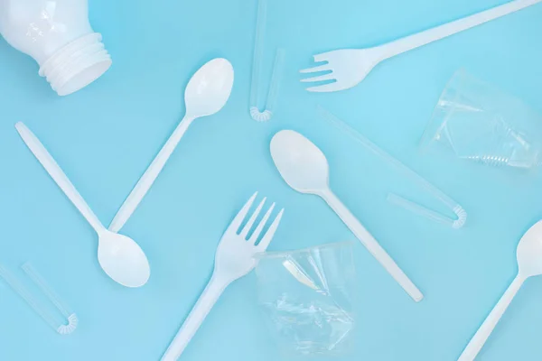 Plastic waste, plastic utensils on a blue background,flat lay. Say no to single use plastic. Ecology environmental care.Copy space for text.