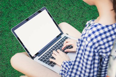 Kadın oturup beyaz dizüstü kullanarak'ın bahçesinde