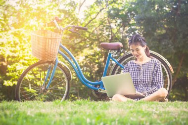 yumuşak odak kadın oturup iş laptop park ve bisiklet kullanarak'ın bahçesinde olduğunu. Vintage tarzı