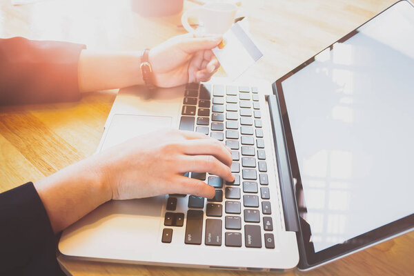 soft focus of woman hand working with laptop and credit card on wooden desk in office in morning light. vintage effect