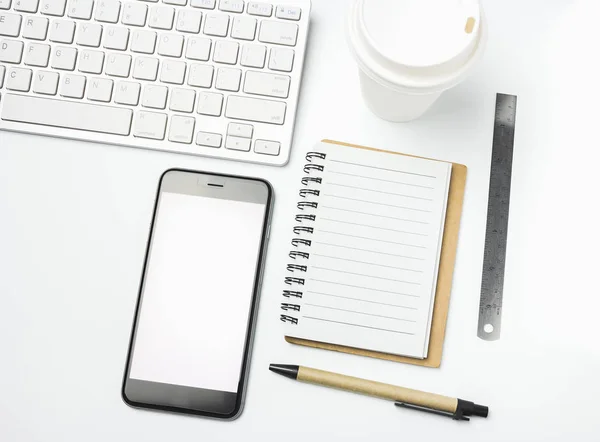 Office workspace with keyboard notepad coffee of cup and smartphone on white background.