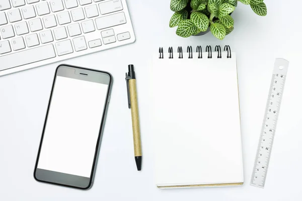 Espaço de trabalho do escritório com caneta de teclado e smartphone em fundo branco. Vista superior — Fotografia de Stock