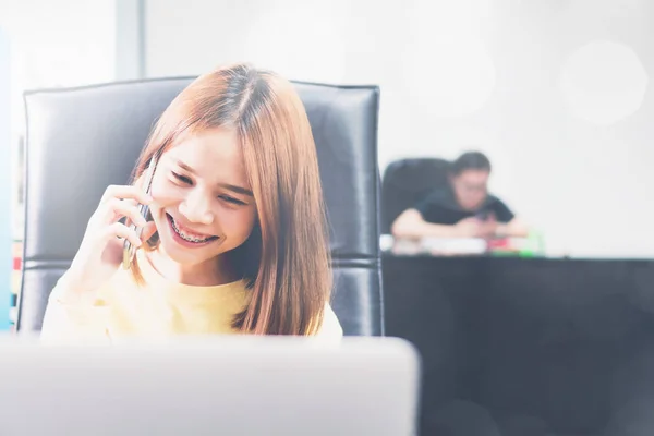 Mladá žena mluví o telefonu v moderní kanceláři a informovat zákazníka — Stock fotografie