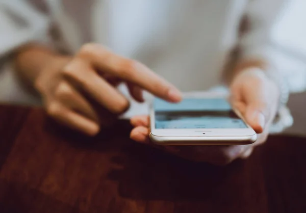 Soft focus of woman hand working with phone on desk in coffee shop. Vintage tone — Stock Photo, Image