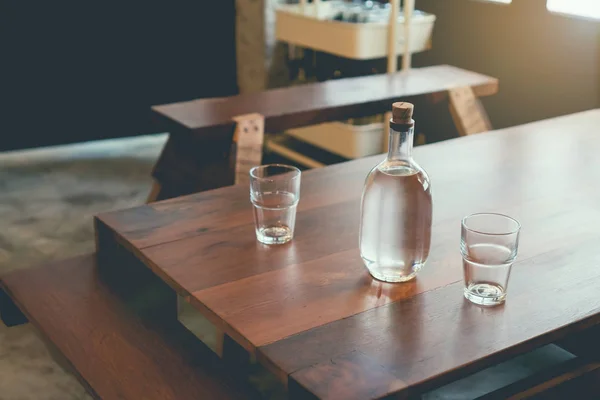 Foco suave de garrafas de água e vidro são colocados em uma mesa de madeira em um café, esperando que os clientes peçam comida. tom vintage — Fotografia de Stock
