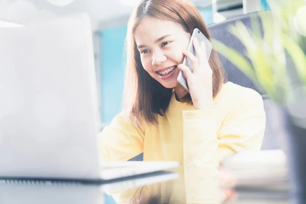 Mladá žena mluví o telefonu v moderní kanceláři a informovat zákazníka — Stock fotografie