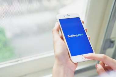 Bangkok, Tayland - 22 Ağustos 2017: Kadınlar bir ekran Booking.com logo ile bir telefon iphone 6 tutun. Online sunan konaklama onun Web ve mobil tabanlı Acenteleri