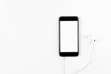 Siyah telefon ve beyaz zemin üzerine beyaz kulaklık. Teknolojik kavramları ilerleme.