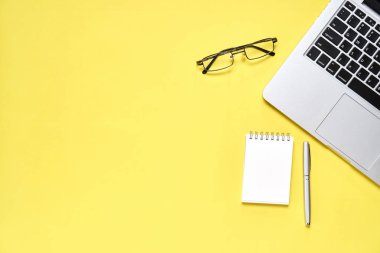 Üstten Görünüm, Modern çalışma alanı ile laptop ve defter kalem pastel sarı bir arka plan yerleştirilen ile. Kopya alanı grafik kullanım için uygun.