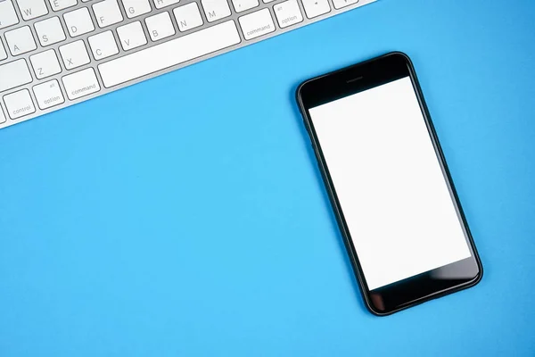 黑屏智能手机空白和键盘与笔记垫放置在蓝色背景。适合用于广告的图形. — 图库照片