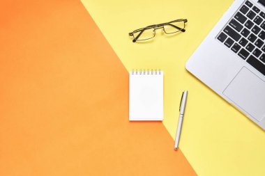 Üstten Görünüm, Modern çalışma alanı ile laptop ve defter kalem pastel sarı bir arka plan yerleştirilen ile. Kopya alanı grafik kullanım için uygun.