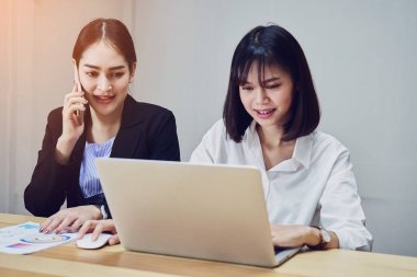 İş kadınları ofiste çalışmak için dizüstü bilgisayarlar ve akıllı telefonlar kullanıyorsunuz. Müşteri hizmet dış kaynak.