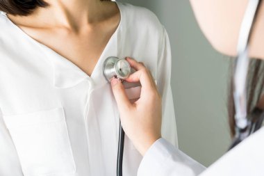 Doktor stetoskop bir hasta hasta muayene için kullanıyor. Kalp hastalığı olan hastalar için kalp atışını duymak.