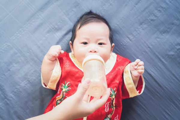 穿着蓝色布的红色连衣裙和吃牛奶的婴儿 概念农历新年 — 图库照片