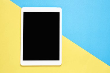 Üstten Görünüm, pastel sarı bir arka plan yerleştirilen tablet ile Modern çalışma alanı. Kopya alanı grafik kullanım için uygun.