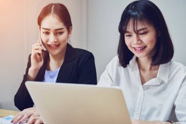 İş kadınları ofiste çalışmak için dizüstü bilgisayarlar ve akıllı telefonlar kullanıyorsunuz. Müşteri hizmet dış kaynak.