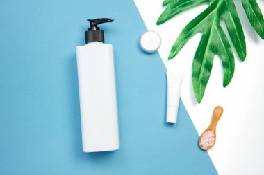 Mockup kozmetik krem şişesi, boş etiket paketi ve malzemelerin bir yeşil yaprakları arka plan üzerine. Doğal güzellik ürünleri kavramı.