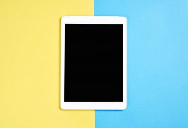 Üstten Görünüm; Tablet ile modern işyeri pastel sarı bir arka plan üzerinde yerleştirilir. Kopya alanı grafik kullanım için uygun.
