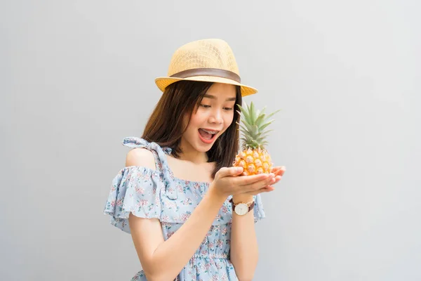 若い女の子の幸せな笑顔 青いドレス 手でホールド パイナップルの陽気 コンセプト夏旅行 — ストック写真