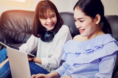 Asyalı kız mavi casual elbise siyah kulaklık ve kullanım laptop müzik. Bir rahat ve iyi ruh hali içinde kanepe oturma odasında.