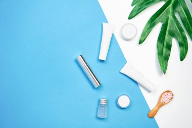 Mockup kozmetik krem şişesi, boş etiket paketi ve malzemelerin bir yeşil yaprakları arka plan üzerine. Doğal güzellik ürünleri kavramı.