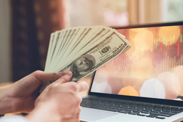 Kvinnas Hand Håller 100 Dollar Och Laptop Skärm Visar Grafen — Stockfoto