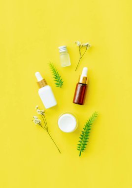Beyaz şişe kremi, güzellik ürünleri markasının maketi. Sarı arkaplanda üst görünüm.