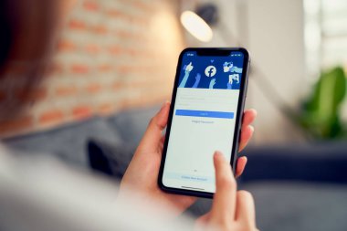 Bangkok, Tayland - 20 Mart 2020: Kadın eli Apple iphone 'da Facebook ekranına basıyor, Sosyal medya bilgi paylaşımı ve ağ paylaşımı için kullanıyor.