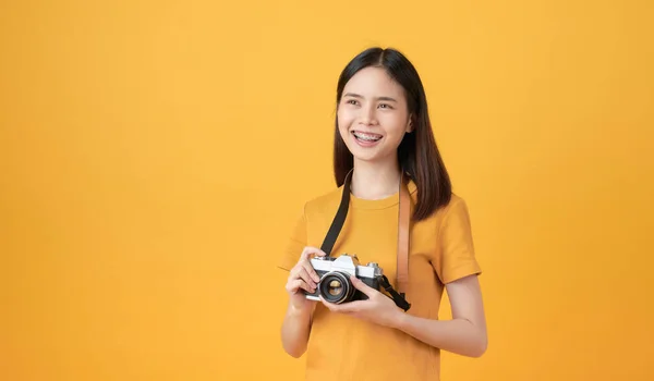 若いです笑顔アジアの女性観光客保持カメラと黄色の背景にスペースをコピーしようと — ストック写真