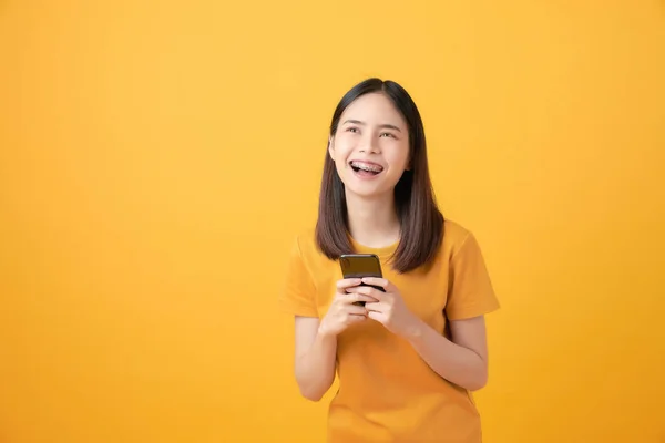 Alegre Hermosa Mujer Asiática Sosteniendo Teléfono Inteligente Sobre Fondo Amarillo —  Fotos de Stock