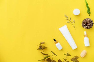 Beyaz şişe kremi, güzellik ürünleri markasının maketi. Sarı arkaplanda üst görünüm.