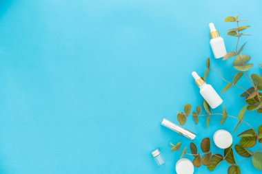 Beyaz şişe kremi, güzellik ürünleri markasının maketi. Mavi arkaplanda üst görünüm.