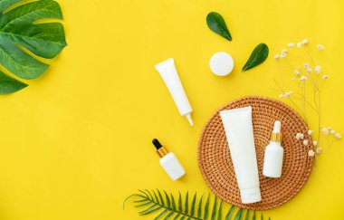 Beyaz şişe kremi, güzellik ürünleri markasının maketi. Sarı arkaplanda üst görünüm.