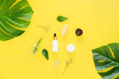 Beyaz şişe kremi, güzellik ürünleri markasının maketi. Sarı arkaplanda üst görünüm.