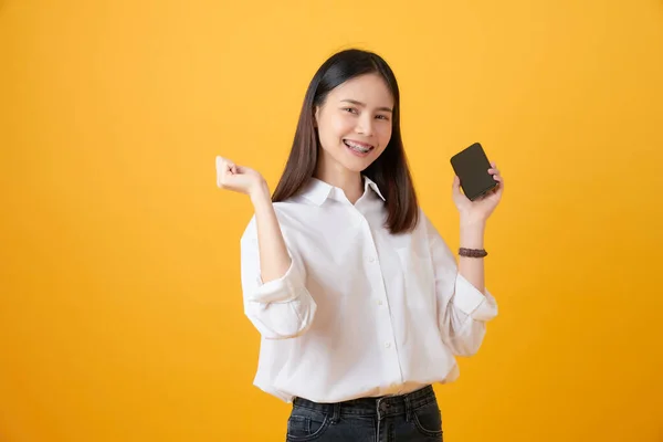 Χαρούμενη Όμορφη Ασιατική Γυναίκα Κρατώντας Smartphone Ανοιχτό Κίτρινο Φόντο — Φωτογραφία Αρχείου