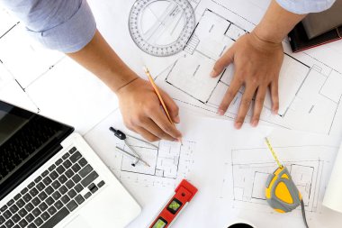 İç mekan tasarımcısı veri ve iş belge ve grafik tasarım diyagramı ile dijital tablet ve bilgisayar laptop kavram olarak ahşap masa üzerinde tartışıyor