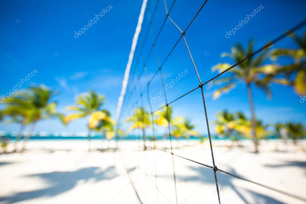 Close-up of volleyball net on tropical beach. Blue sky and palms of the Caribbean sea. Holidays in Punta Cana, Dominican Republic. Beach sports