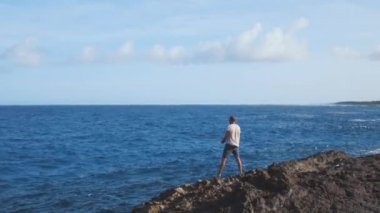 Bir balıkçı oltayı denize atıp oltayla oltayı çevirir. Mavi Karayip denizinde kayalık balıkçılığı