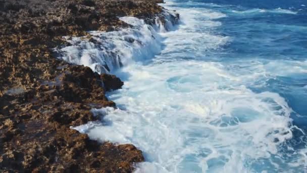 大きな海の波が岩に衝突した ターコイズブルーの水が形成され 崖から流れ落ちます 熱帯の島の自然の偉大さと力を持つ穏やかな背景 — ストック動画