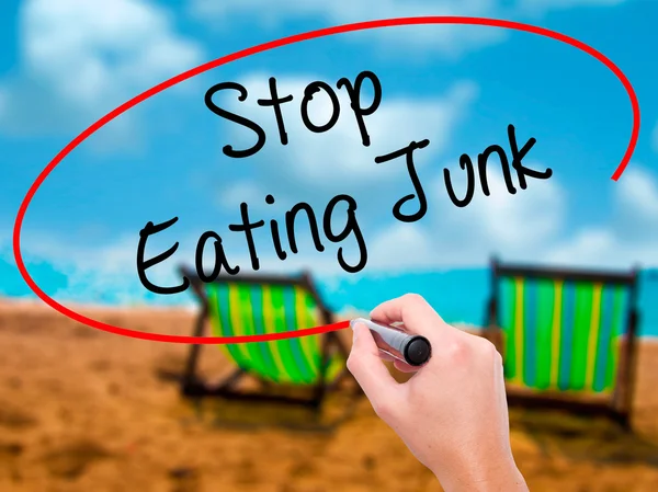 Man Hand writing Stop Eating Junk with black marker on visual sc