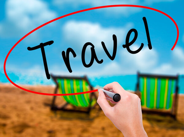 Man Hand writing Travel with black marker on visual screen. Isolated on sunbed on the beach. Business, technology, internet concept. Stock Image