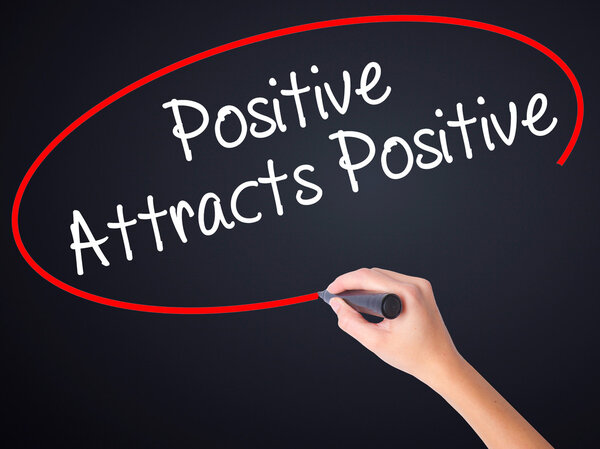 Woman Hand Writing Positive Attracts Positive with a marker over
