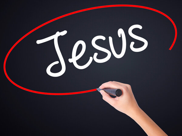Woman Hand Writing Jesus  with a marker over transparent board 