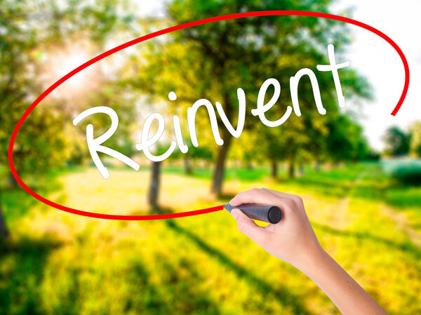 Woman Hand Writing  Reinvent with a marker over transparent boar